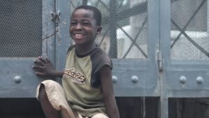 smiling boy sitting beside gray metal board