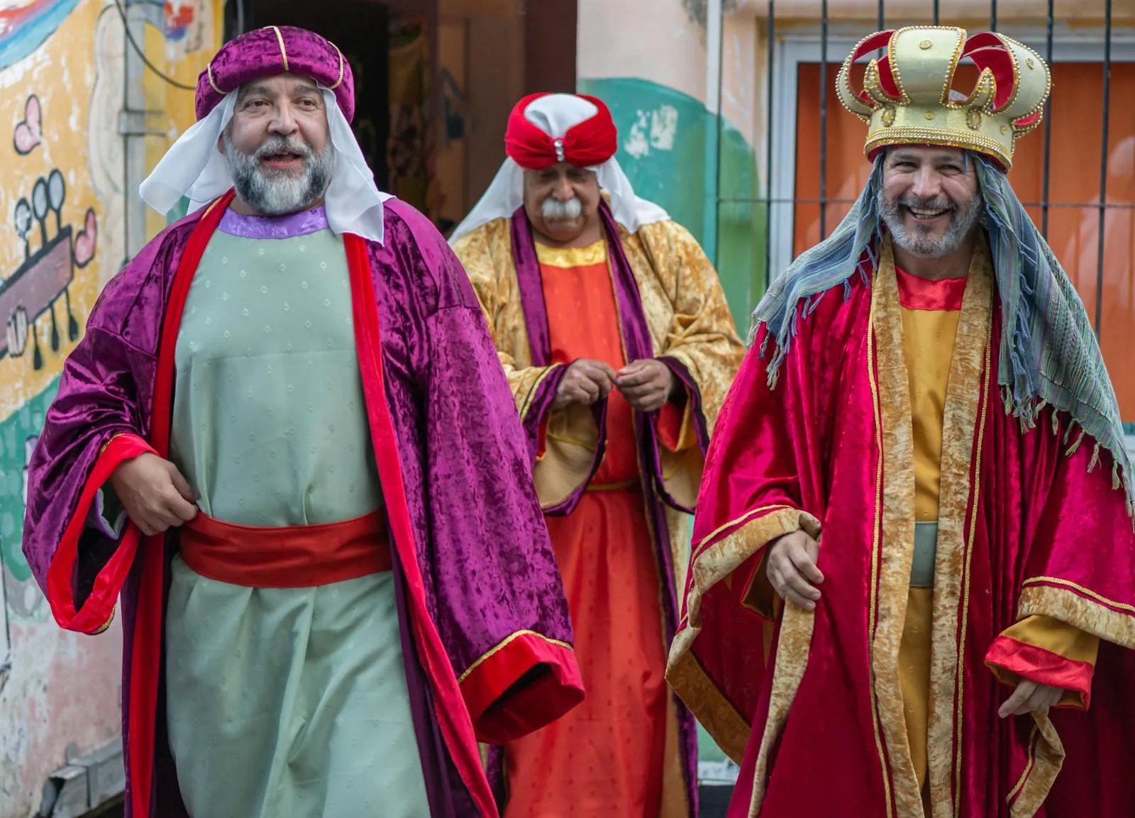 Three men dressed as the Magi in a colorful street festival, celebrating tradition and joy.