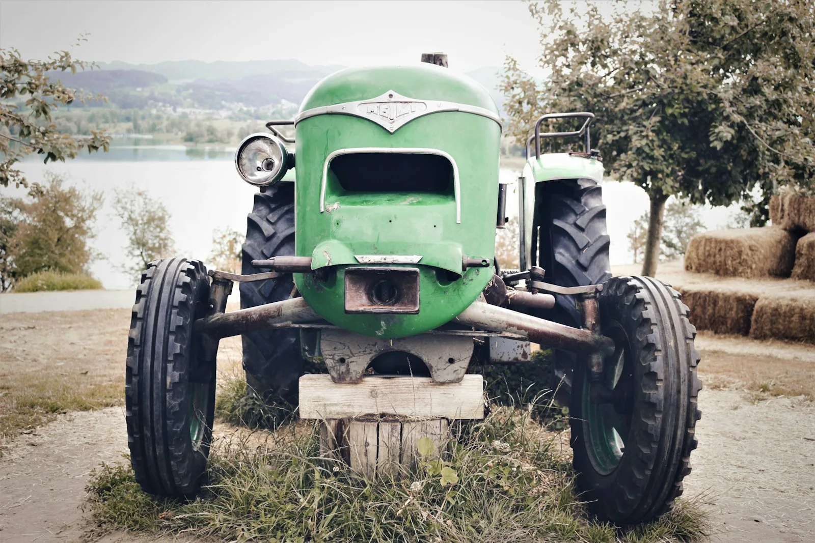 selective focus photography of green tractor near body of water