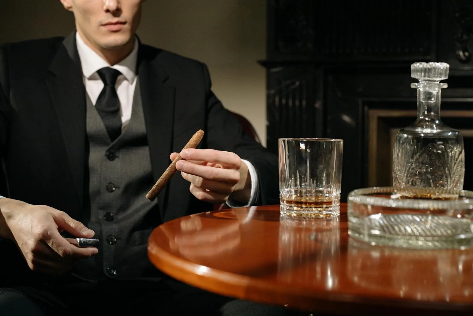 An elegant man in a suit holding a cigar beside a whiskey glass, exuding mystery and class.