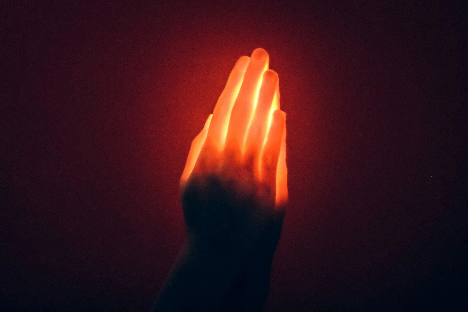 A hand holding a glowing object in the dark