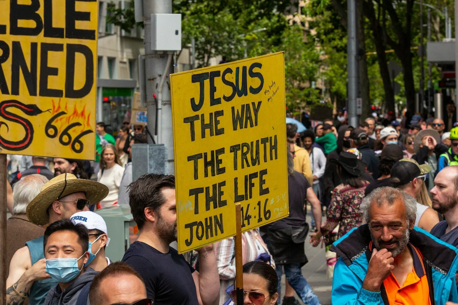 a crowd of people walking down a street holding signs