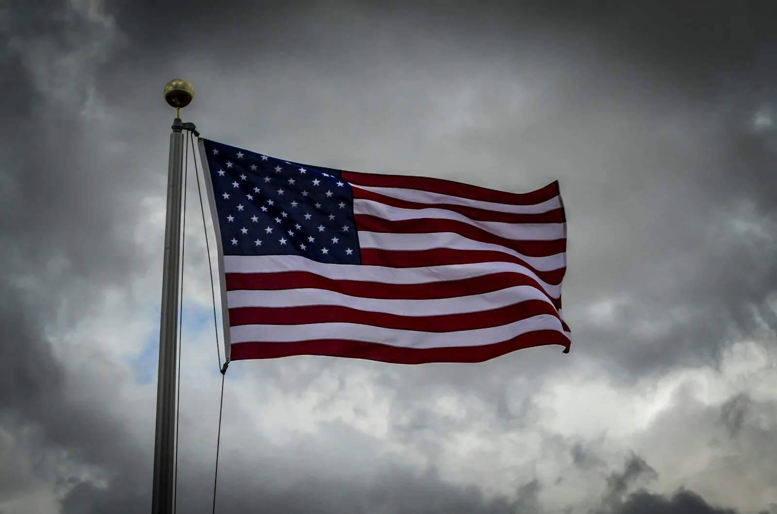 An american flag flying in a cloudy sky
