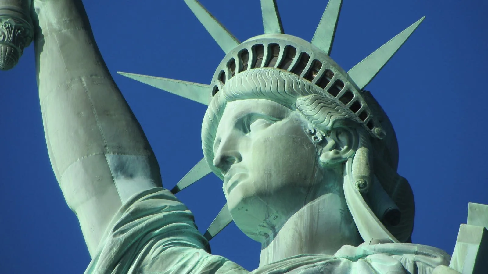 Detailed close-up of the Statue of Liberty in New York City against a clear blue sky.