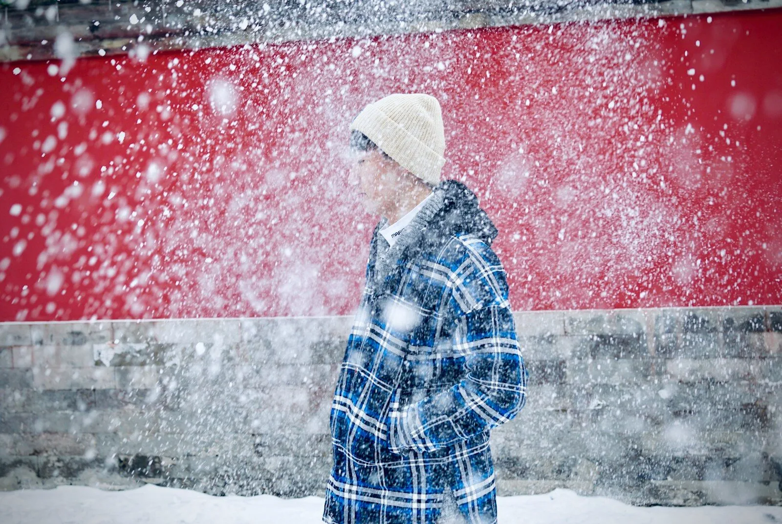 a person walking in the snow in front of a red building