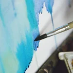 Artist painting abstract blue watercolor on canvas.