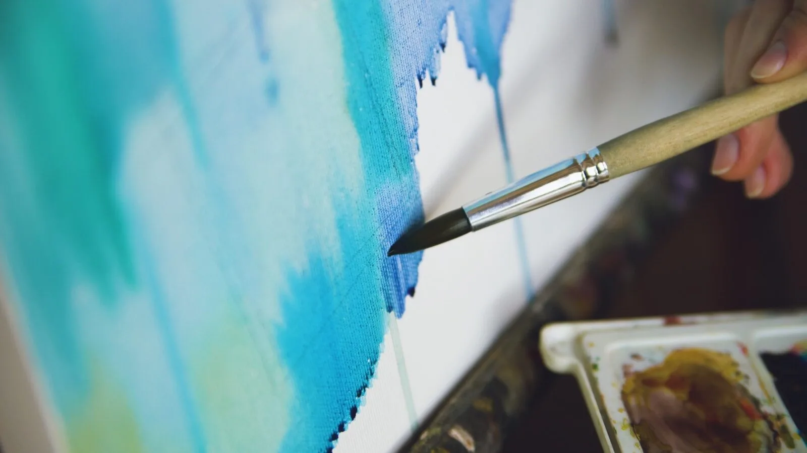 Artist painting abstract blue watercolor on canvas.